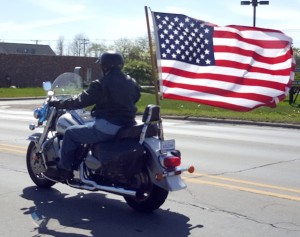A motorcyclist flies the American Flag down Lapeer Rd. 