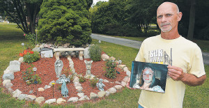 Christopher Woityra holds a photo his late daughter Taylor Beth as he stands near the memorial garden he created in the shape of a peace sign. Photo by C.J. Carnacchio.