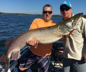 Orion Twp. residents Tim Berger (left) and Ethan Beckman pose with the 60-inch muskie they landed in Ontario, Canada’s North Channel on July 26. Not pictured is Oxford resident Tom Berger, who was part of the team that landed this beast. Photo provided.