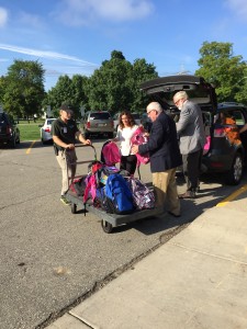 State Senator Jim Marleau, State Representative Bradford Jacobsen and Principal Goethals load backpacks to take into Blanch Sims.