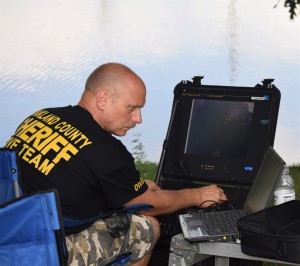 Sgt. Dave Bach of the Oakland County Sheriff’s Dept. Dive Team uses an ORV remote underwater camera to search the bottom of an Orion Township pond for evidence in an ongoing case. Photos by Jim Newell