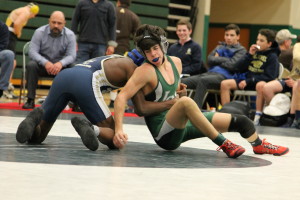 Dragon wrestler Nick Nowakowski (in green) grapples with an opponent during the team district wrestling competition Feb. 9. Photo by Darin Smith