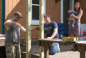 Lake Orion Police Officers Lt. Harold Rossman (right) and Reserve Officer Frank Scarpaci rebuild the Biton’s back porch as Ivette and 5-month-old Gabriel watch. Photo by Susan Carroll.