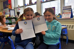 Arianna (left) and Juliana hold up the letters they wrote for sailors aboard the USS John C. Stennis.